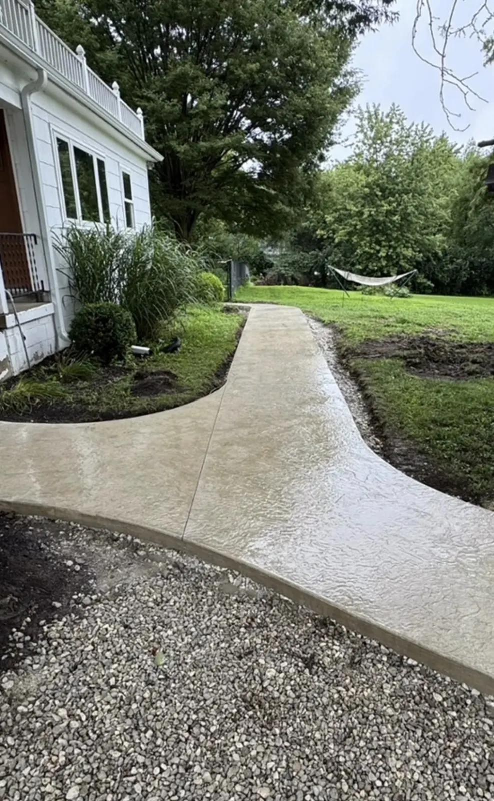 Curved residential concrete sidewalk through landscaped yard